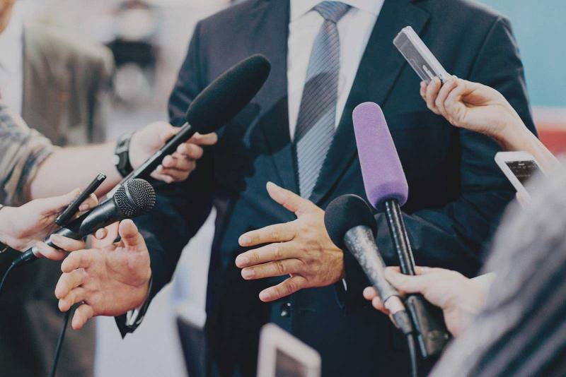 Mikrofone von Journalisten vor einer Person im Anzug